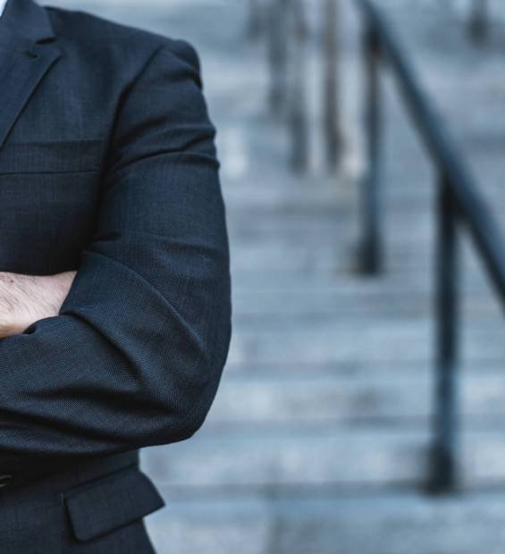 Close-up businessman  crossing his hands posing against the background of the office stairs blurred background.